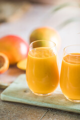 Two mango lassi or kesar milk in glasses. Indian healthy ayurvedic cold drink with mango. Freshness lassi made of yogurt, water, spices, fruits and ice.
