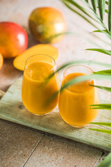Two mango lassi or kesar milk in glasses. Indian healthy ayurvedic cold drink with mango. Freshness lassi made of yogurt, water, spices, fruits and ice.