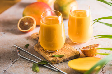 Two mango lassi or kesar milk in glasses. Indian healthy ayurvedic cold drink with mango. Freshness lassi made of yogurt, water, spices, fruits and ice.
