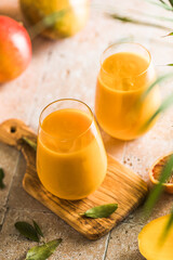 Two mango lassi or kesar milk in glasses. Indian healthy ayurvedic cold drink with mango. Freshness lassi made of yogurt, water, spices, fruits and ice.