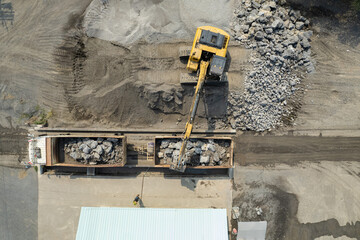 excavator scooping rocks, stone construction