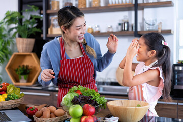 Young mother teach daughter in the kitchen learn online cooking clean food from the laptop computer