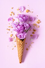 Wafer (waffle) cone with tulips on a pink background. Flower ice cream, spring concept with first flowers.