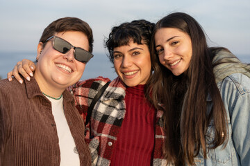 Three Friends Embracing and Smiling by the Seaside