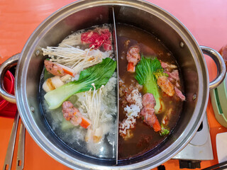 sukiyaki and suki shabu in a pan with tomyam sauce and a composition of enoki mushrooms, Tremella fuciformis, prawns, meat and more