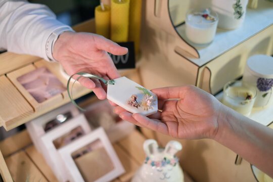 Handmade Aromatic Sachet Sale: A woman at a market hands over artisanal sachet to a customer, showcasing craftsmanship and natural scents.