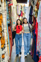 Female tourists shopping clothes in street bazaar