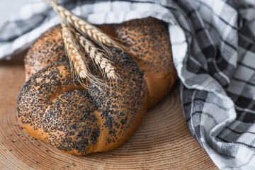 Classic wheat braid with poppy seeds. Delicious bread close-up. Freshly baked sourdough bread with a golden crust on a wooden board. The context of a bakery with delicious bread. 
