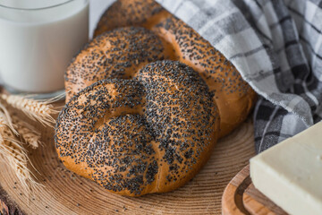 Classic wheat braid with poppy seeds. Delicious bread close-up. Freshly baked sourdough bread with a golden crust on a wooden board. The context of a bakery with delicious bread. 