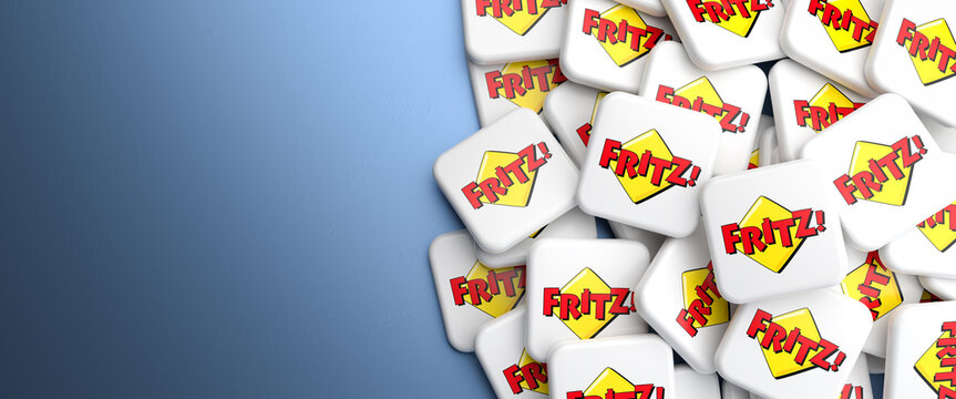 Logos of the brand Fritz (Fritz box routers by the company AVM)  on a heap on a table. Web banner format, copy space.