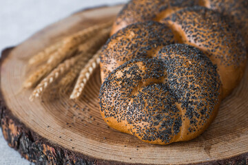 Classic wheat braid with poppy seeds. Delicious bread close-up. Freshly baked sourdough bread with a golden crust on a wooden board. The context of a bakery with delicious bread. 