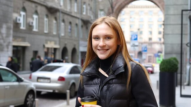 Face young sunshine woman with red hair look at camera smile stand in the city streets beautiful lady portrait happy outdoor close up slow motion