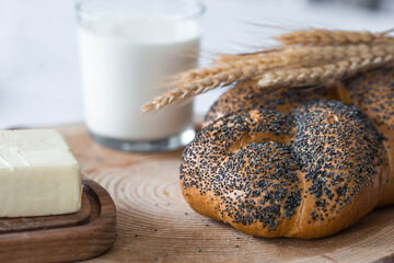 Classic wheat braid with poppy seeds. Delicious bread close-up. Freshly baked sourdough bread with a golden crust on a wooden board. The context of a bakery with delicious bread. 