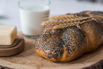 Classic wheat braid with poppy seeds. Delicious bread close-up. Freshly baked sourdough bread with a golden crust on a wooden board. The context of a bakery with delicious bread. 