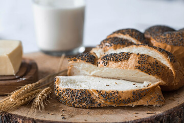 Classic wheat braid with poppy seeds. Delicious bread close-up. Freshly baked sourdough bread with a golden crust on a wooden board. The context of a bakery with delicious bread. 
