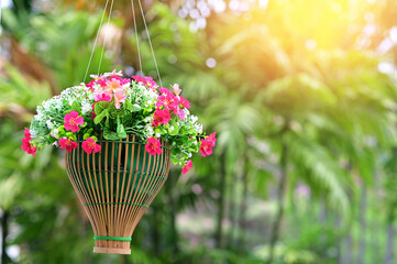 Multi-colored of fake flowers in the wooden basket  in the park with natural background at Thailand for design and decoration.