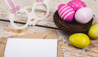 colored easter eggs and rabbit and envelope and blank for text on wooden background easter minimal flat lay top view