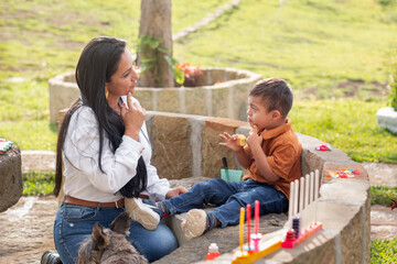 A woman teaches her son with Down syndrome to chew food on a beautiful sunny day in a nature park.