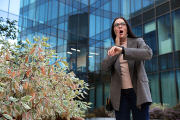 Emotional woman checking time on watch outdoors. Being late concept