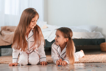 Playing card game. Two little girls are together in domestic room