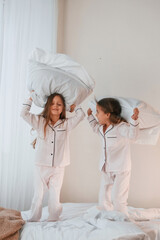 Obraz na płótnie Canvas Playing pillow fight. Two little girls are having fun together in domestic room