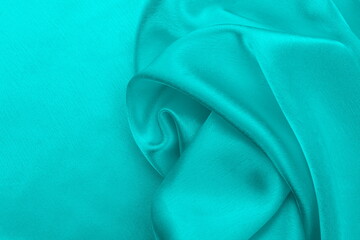 Satin beautiful silk fabric in turquoise color lies with drapery.	