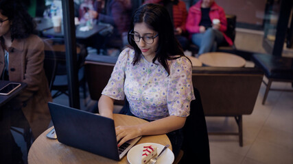 Woman working on laptop in cafe. Close-up portrait of nice-looking multi-race brunette beautiful elegant young woman looking into computer. Daily people life, fashion, beauty. Female portraits. 4k UHD