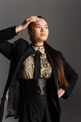 Trendy asian model in jacket and shirt with animal print posing isolated on grey.