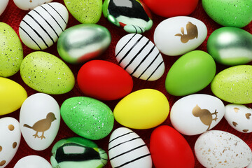 Many beautifully decorated Easter eggs on red background, flat lay
