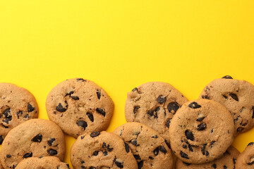 Many delicious chocolate chip cookies on yellow background, flat lay. Space for text