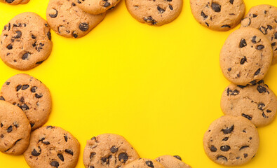 Frame made of many delicious chocolate chip cookies on yellow background, flat lay. Space for text