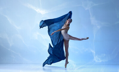 Ballerina dancing graceful movement with silk fabric over blue background © Lustre Art Group 