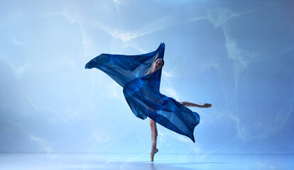 One emotional ballerina wearing bodysuit dancing with silk on fingertips with hands over blue background © Lustre Art Group 
