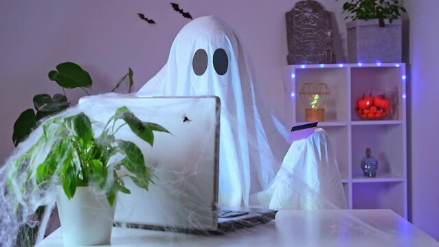 Ghost of Halloween uses laptop surf the Internet, browse online stores, markets. A ghost makes an order from computer for Halloween. Ghost pays for online purchase by credit, bank card.