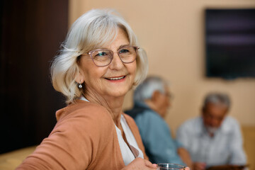 Portrait of happy senior woman day dreaming in residential care home.