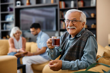 Happy senior man enjoys in cup of tea at nursing home and looking at camera.