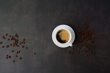 Coffee cup with roasted beans on stone background. Top view with copy space