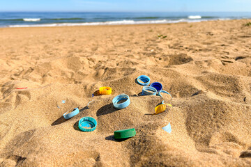 Plastic bottle caps discarded on the beach, ecological problem