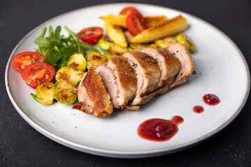 Grilled duck breast fillet with Brussels sprouts, mini corn, cherry tomatoes, arugula and lingonberry sauce. Traditional Mediterranean cuisine. Selective focus, close-up.