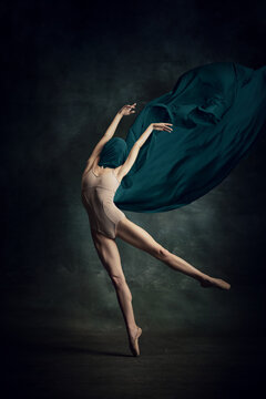 Shot of one adorable ballerina dancing with elegance hands and silk fabric over dark green background