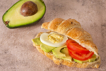 Healthy avocado, tomato, egg and croissant sandwich. Healthy food concept