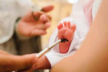 Baptism ceremony of a baby. Close up of tiny baby feet, the sacrament of baptism. The godfather...