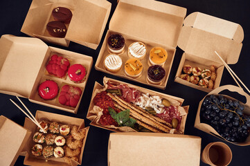 Close up view of table with food on it. Meat, vegetables, sushi, French fries, burger, mushrooms