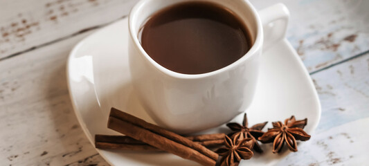 a Cup of coffee with cinnamon sticks on a light wooden background.Horizontal wide photo subtitle, cover. copy-spaceHorizontal wide photo subtitle, cover. copy-space