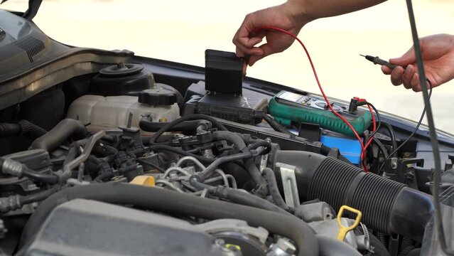 technician checks the battery using a voltmeter capacity tester,auto mechanic uses a multimeter voltmeter to check the voltage level in a car battery