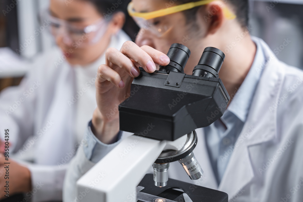 Wall mural scientist analyzing microscope slide at laboratory. young woman technician is examining a histologic