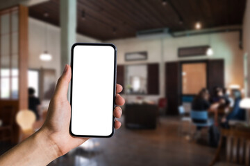 Mockup image of hand holding white mobile phone with blank white screen in cafe.