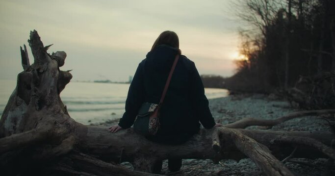 Young Woman Seeking Mental Health Therapy Sits Alone on Secluded Beach in Solitude. Concept of Coping with Depression, Stress, Suicide, Grief, and Anxiety 4k