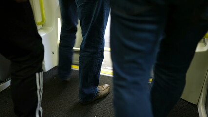 People leaving and entering subway train on platform. Close up legs on crowded transportation