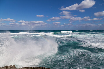 Big wave crashes against the volcanic lava rocks of a sea shore.